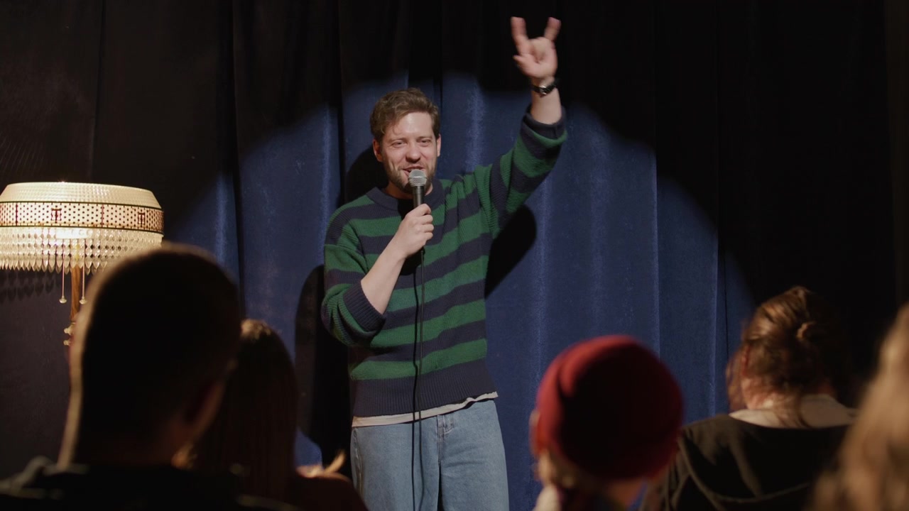 Presentatrice che accoglie un comico ospite sul palco in un locale di stand-up comedy