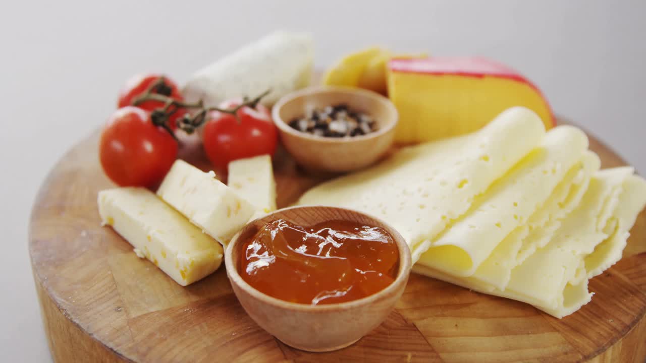 Different types of cheese, tomatoes and bowl of jam