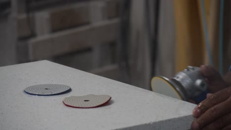 close-up of a person polishing a countertop surface with an orbital sander in a workshop