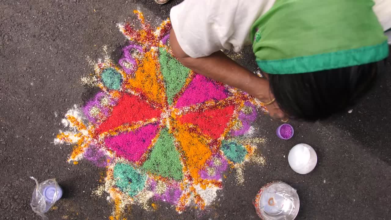 Una donna crea un motivo di riso colorato in preparazione per una cerimonia nuziale