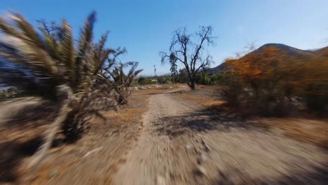 fpv flight over hilly paths and farm field landscape