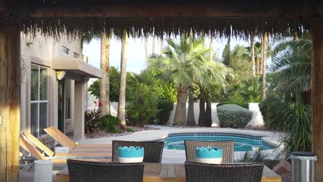 tropical cabana by outdoor swimming pool in luxury vacation home backyard