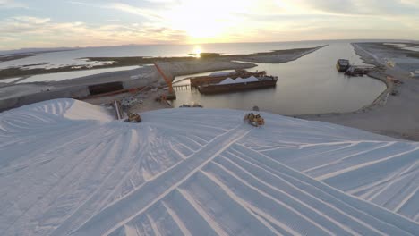 Aerial-shot-of-tractors-working-on-a-large-salt-deposit-in-the-salt-flats-by-solar-evaporation-in-Guerrero-Negro,-Ojo-de-Liebre-lagoon,-Biosphere-Reserve-of-El-Vizcaino,-Baja-California-Sur