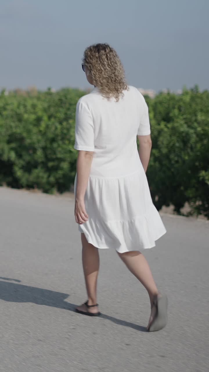 Donna con un vestito bianco che cammina su una strada