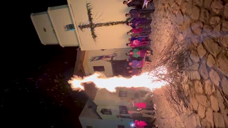 People-gather-around-a-large-bonfire-at-night-in-front-of-a-church-in-Iruya,-Argentina