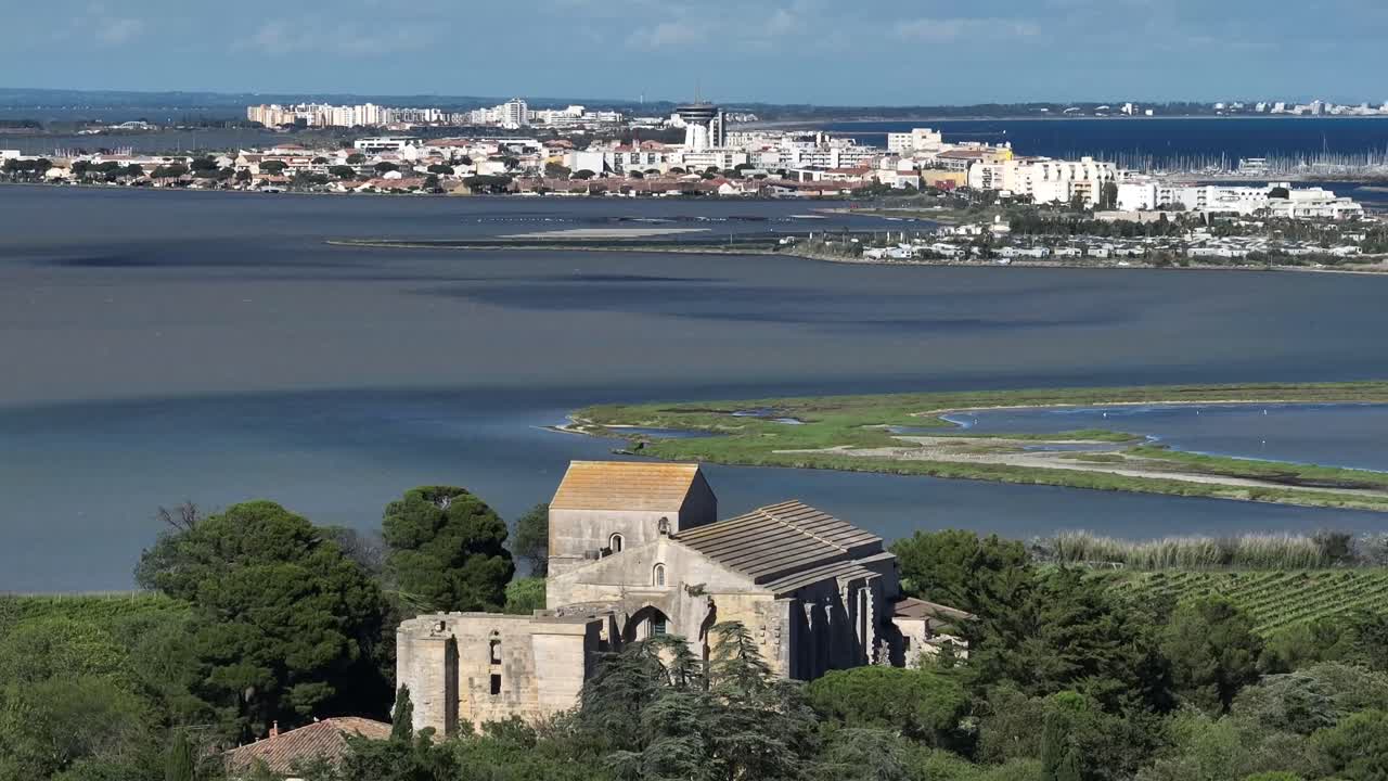 Coastal town of Maguelone in France and its cathedral over lagoon, Aerial pan right shot