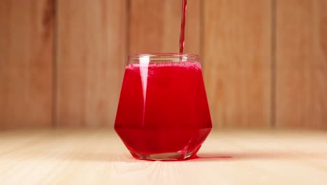 red drink being poured into a glass