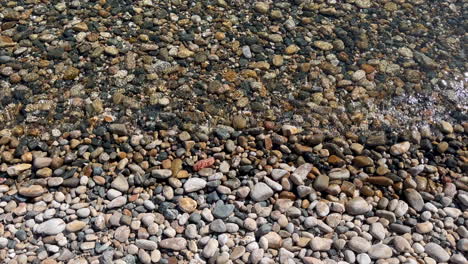 soothing view of small waves flowing over beach pebbles at fokos beach at greece's mykonos island. perfect for travel, nature, peaceful, or meditation video content