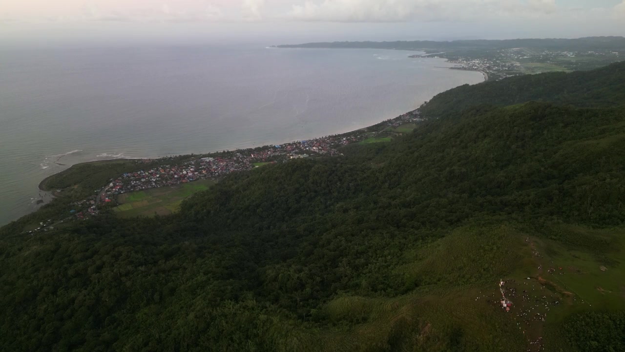 Pemandangan udara panorama Gunung Lantad yang menghadap Virac, Catanduanes, Filipina dengan lanskap pesisir, bukit berhutan, dan garis pantai di kejauhan.