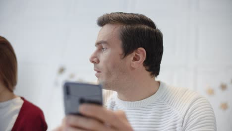 serious man looking mobile in private house. tired couple talking each other