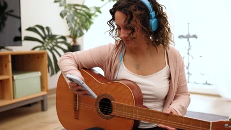 Woman with headphones and guitar browsing her smartphone
