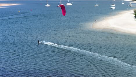 Se-Elevan-Al-Fondo-Mientras-Un-Kitesurfista-Disfruta-De-Ligeros-Vientos-En-La-Costa-Dorada-De-Glourios