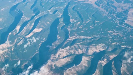aerial drone view of dramatic snow-covered mountains and river valleys in winter terrain
