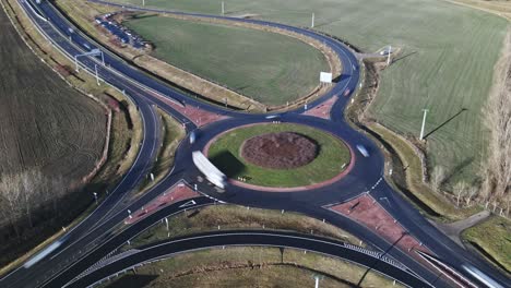 an aerial time-lapse video of a roundabout with cars and trucks moving at high speed. the video captures a well-structured road network, connected highways in the background.