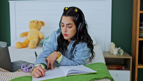 woman studying on bed with laptop and headphones