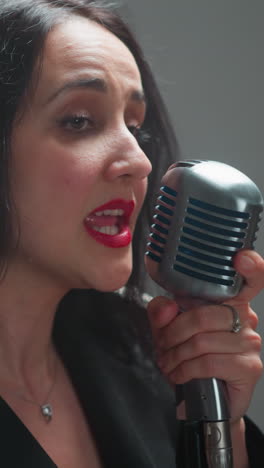 vocalista femenina apasionada cantando con profunda emoción, moviendo su mano expresivamente mientras sostiene un micrófono vintage, en un fondo borroso mientras la cámara se mueve