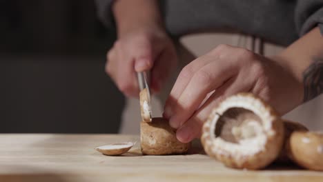 female hands cutting mushrooms using a knife - close up