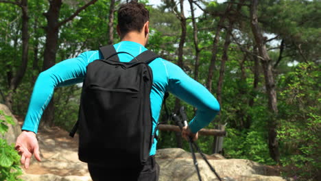 following man jumping on rocky trail while hiking in mountain forest