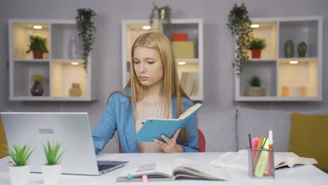 estudiante trabajando entre el papel y la computadora portátil.