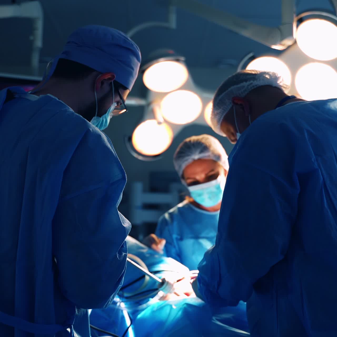 Surgical process in the operating room. Medical lamp switches on during surgery. Group of specialists operate patient in the hospital.