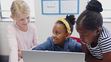in school, three girls using laptop together, collaborating on project
