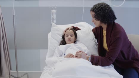 worried biracial mother stroking her sleeping sick daughter patient in hospital in slow motion