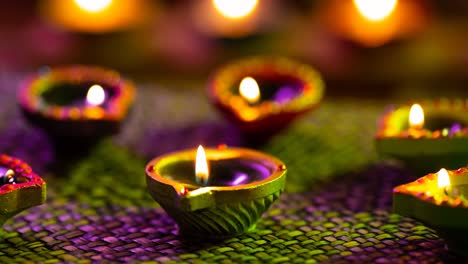 video de velas de diwali encendidas brillantes en una superficie tejida de púrpura a verde