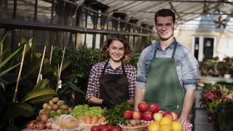 Porträt-Von-Schönen-Bauern-Mann-Und-Frau-In-Schürzen,-Die-Bio-Lebensmittel-Auf-Dem-Bauernmarkt-Verkaufen