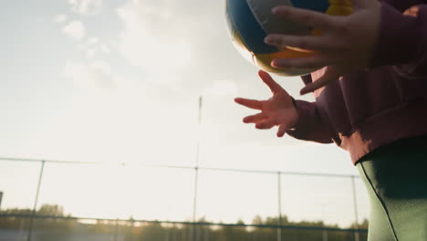 close-up partial view of woman bouncing volleyball with sunlight glow in background, creating a vibrant effect with greenery, showing outdoor sports and healthy lifestyle