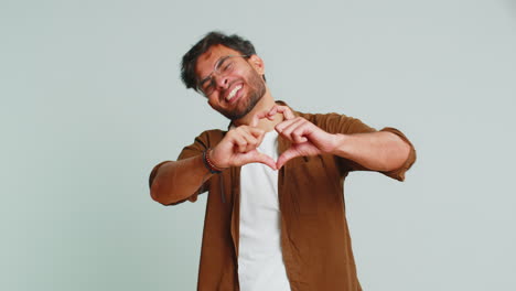 hombre guapo sonriente hace un gesto de corazón demuestra un signo de amor expresa buenos sentimientos y simpatía