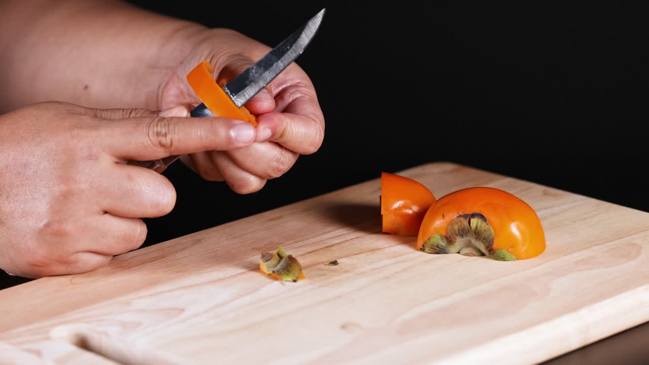 손 이 익은 파시몬 과일 을 조심스럽게 잘라내는 것
