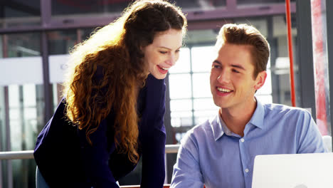 Business-executives-discussing-over-laptop