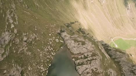 above the majestic turquoise mountain lake, the fpv drone descends rapidly, tracing the stream's enchanting path and capturing mesmerizing waterfalls