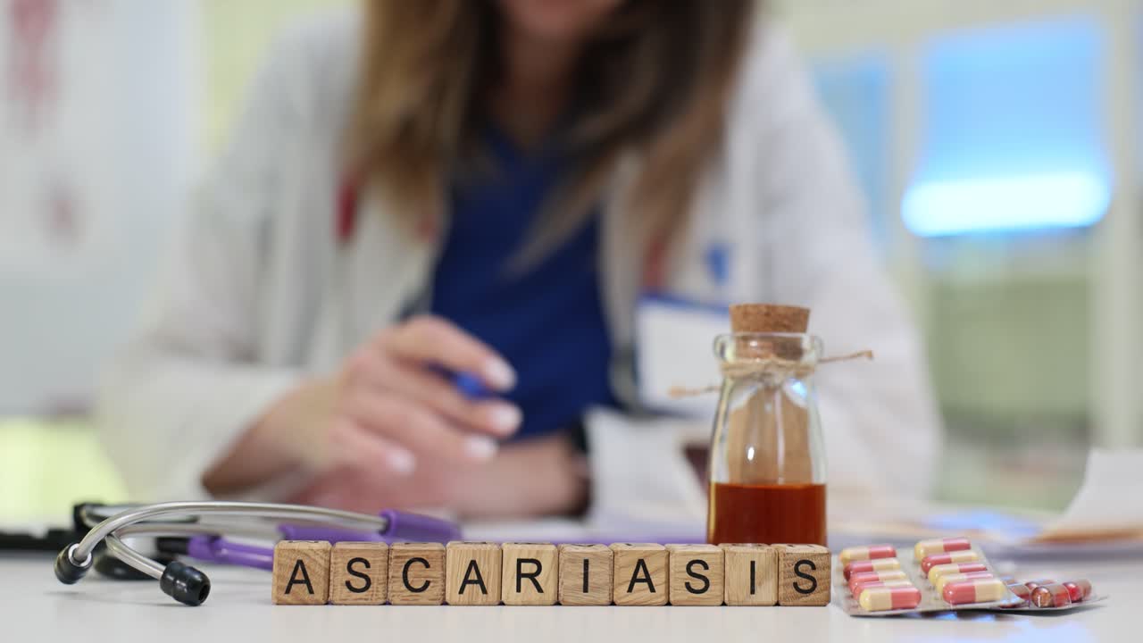 Blocchi di legno compongono la parola ascaridiasi su una scrivania affollata di clinica