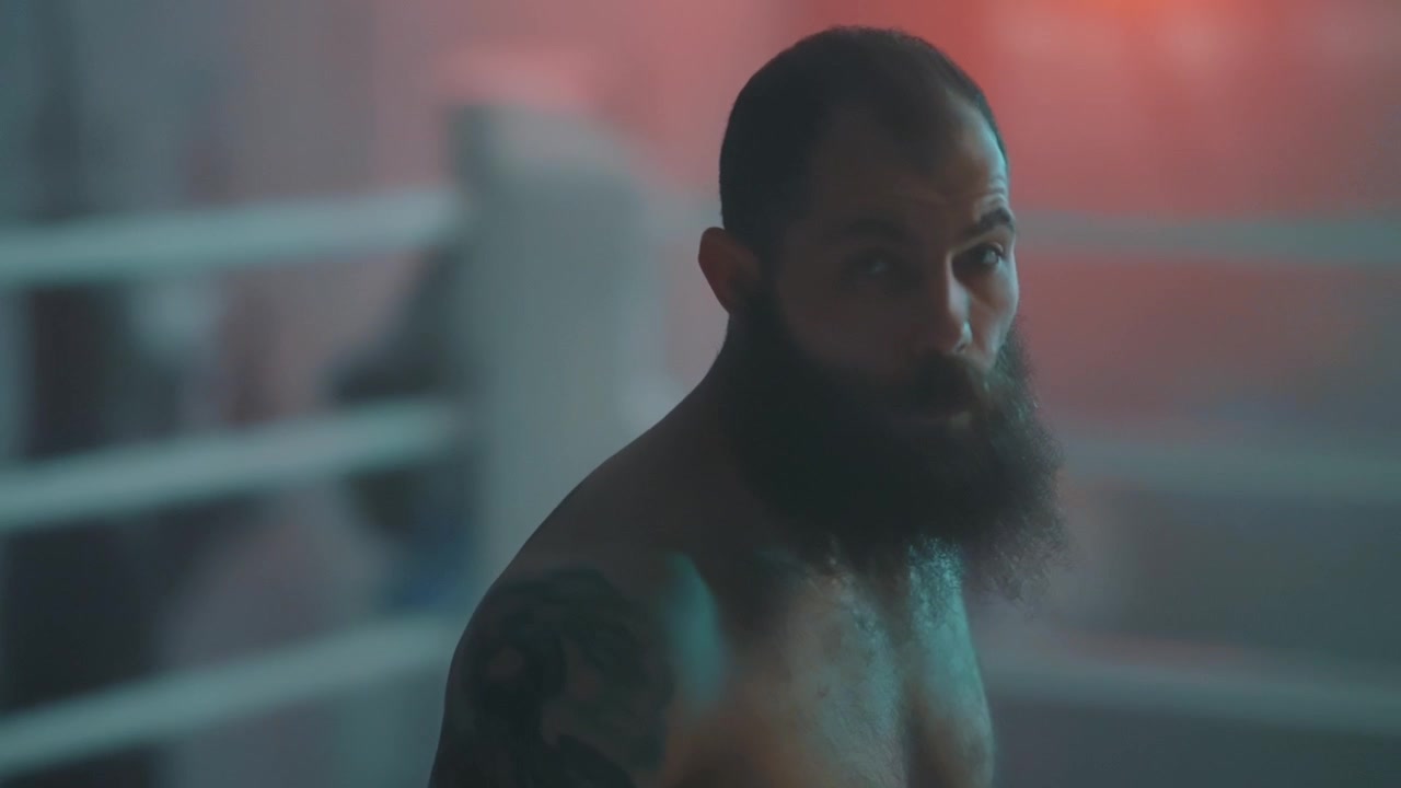 Uomo barbuto intenso con tatuaggi sul ring di pugilato