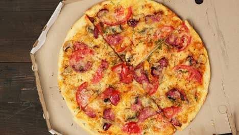 pizza redonda horneada con salchichas, tomates y queso en una caja de cartón blanca
