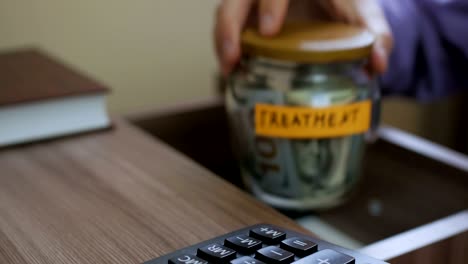 caucasian male putting a glass jar put in a drawer  table with his savings for future treatment