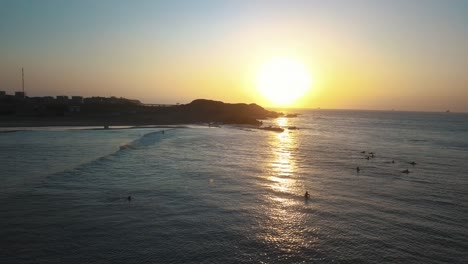 surfers waiting in the calm sea for the perfect wave during beautiful sunset in peru