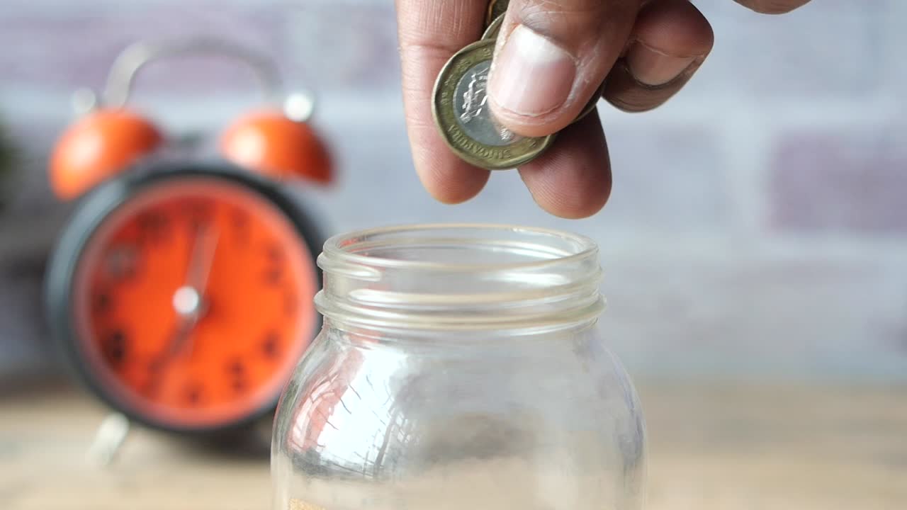 A Person Saving Coins in a Glass Jar