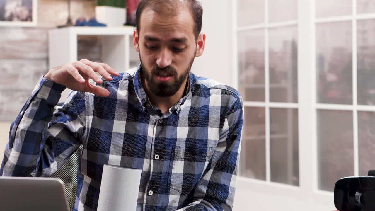 Man in plaid shirt in office with cup