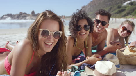 mixed race group of friends hanging out on the beach on summer vacation