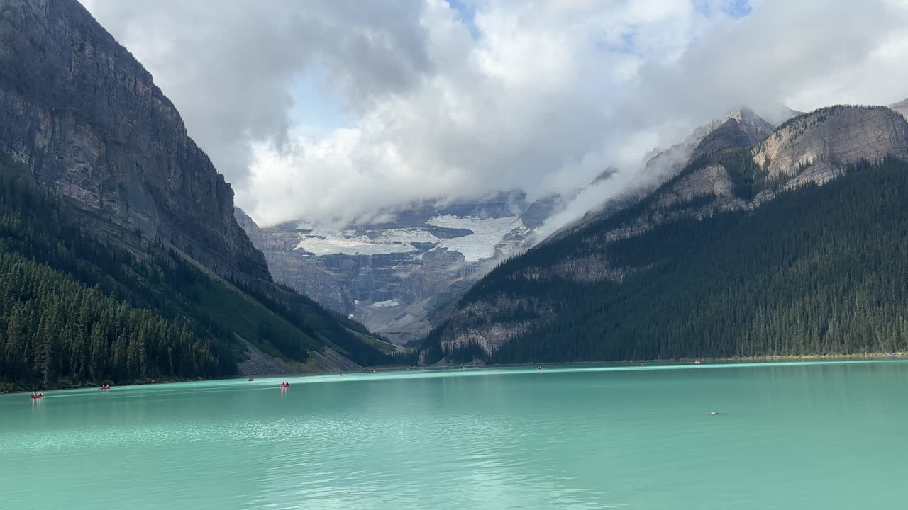 grupo de turistas en kayak en el lago louise durante un día nublado