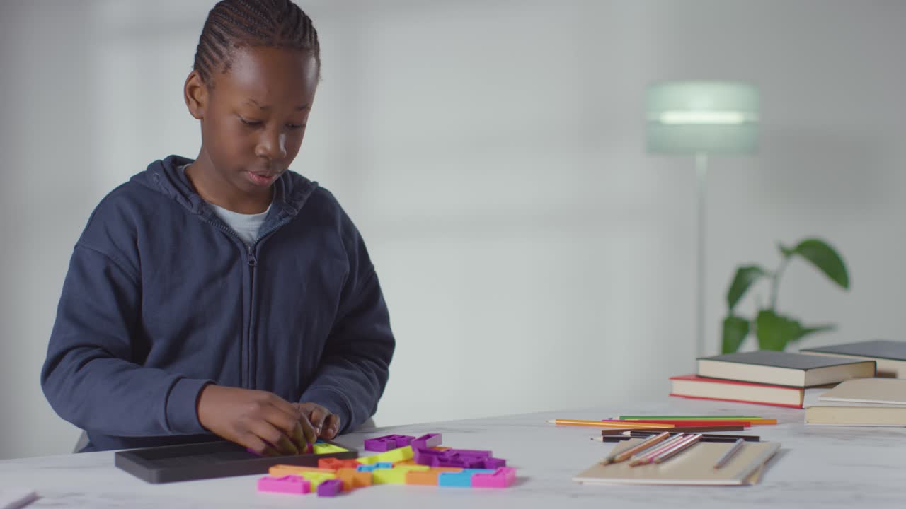 Boy On ASD Spectrum At Home Solving Shape Puzzle Sitting At Table 1