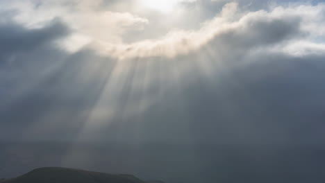 dramatic sun rays piercing through dark clouds