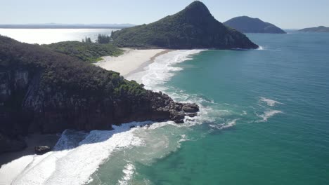 Rocky-Coastline-Of-Beach-To-The-Tomaree-Mountain-On-A-Sunny-Summer-Day-In-Shoal-Bay,-NSW,-Australia