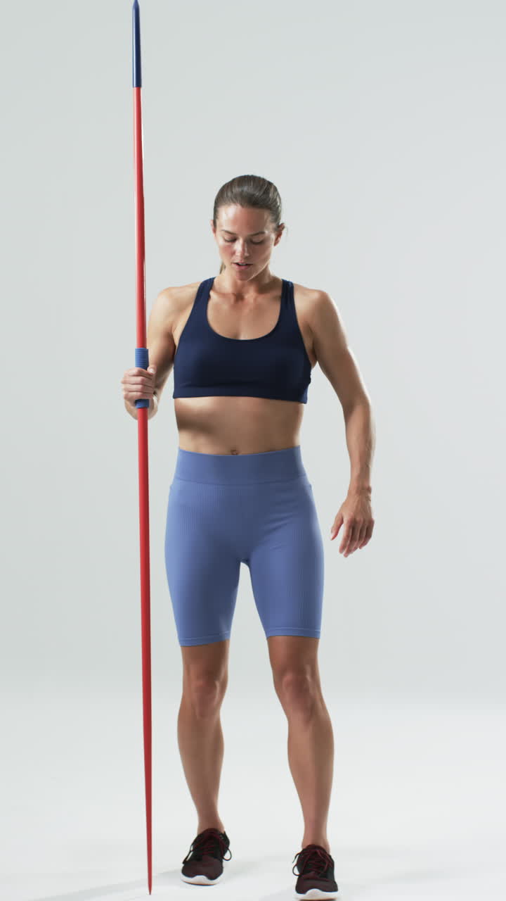 Vertical video: Holding javelin, woman in sportswear standing confidently, preparing for training