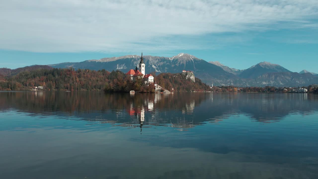 vista aérea del lago sangrado con un hermoso reflejo mientras el dron vuela hacia el lago con los alpes al fondo