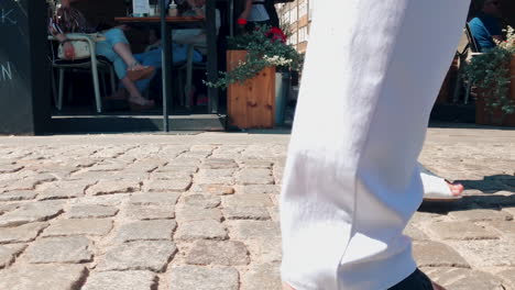 la gente camina en una acera llena de gente, cierra la vista de la acera y las piernas a la altura de la rodilla, cámara lenta en zapatos y pasos