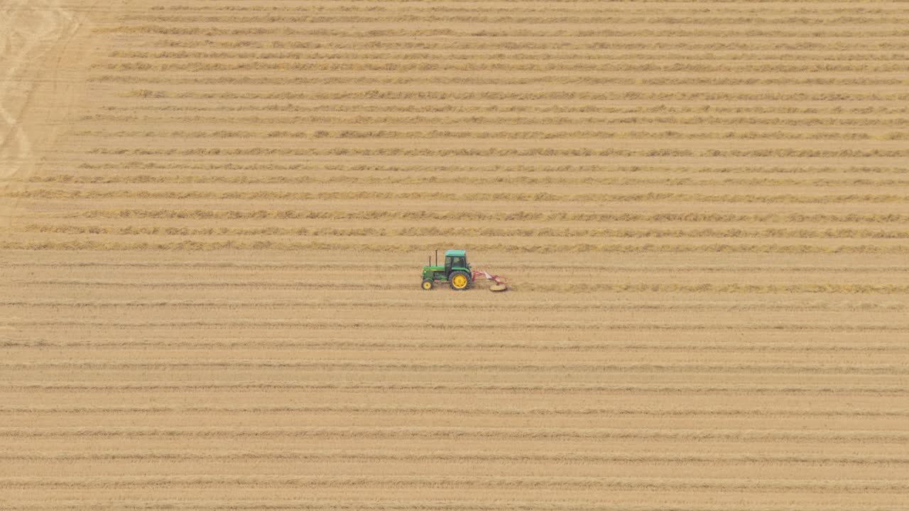 Veduta aerea di un trattore che ara un terreno agricolo con edifici agricoli, Paesi Bassi