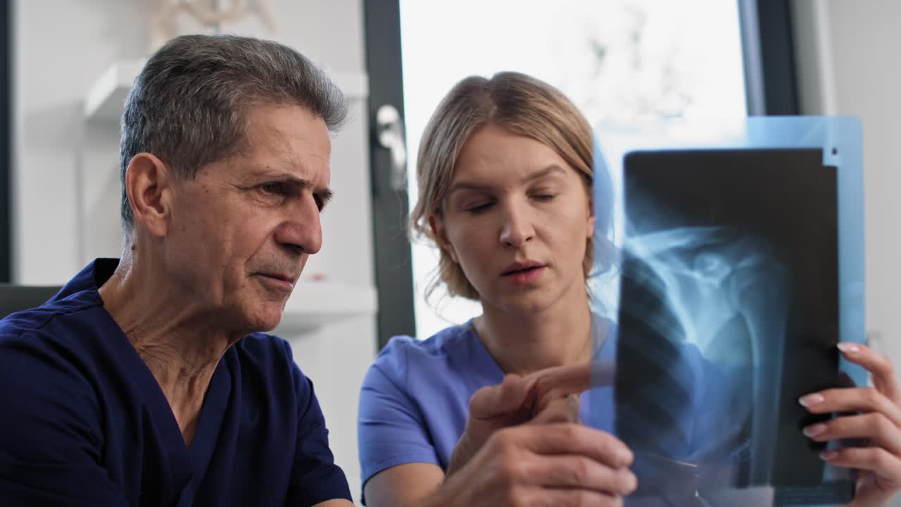 dos médicos caucásicos discutiendo sobre una imagen de rayos x.